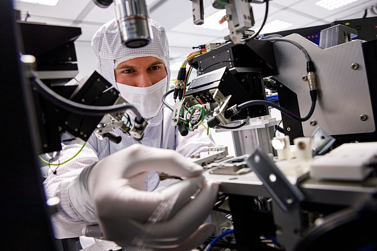 A researcher in cleanroom garb assembles a prototype processor at a probe station in the FMN Laboratory in Moscow.