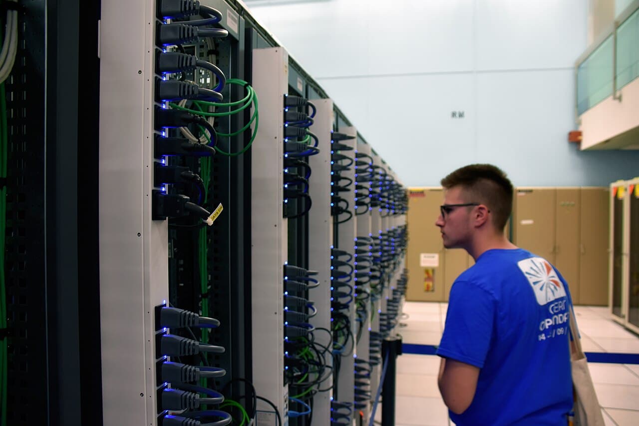 A visitor looks down an aisle of cabled server racks at the CERN computer centre.