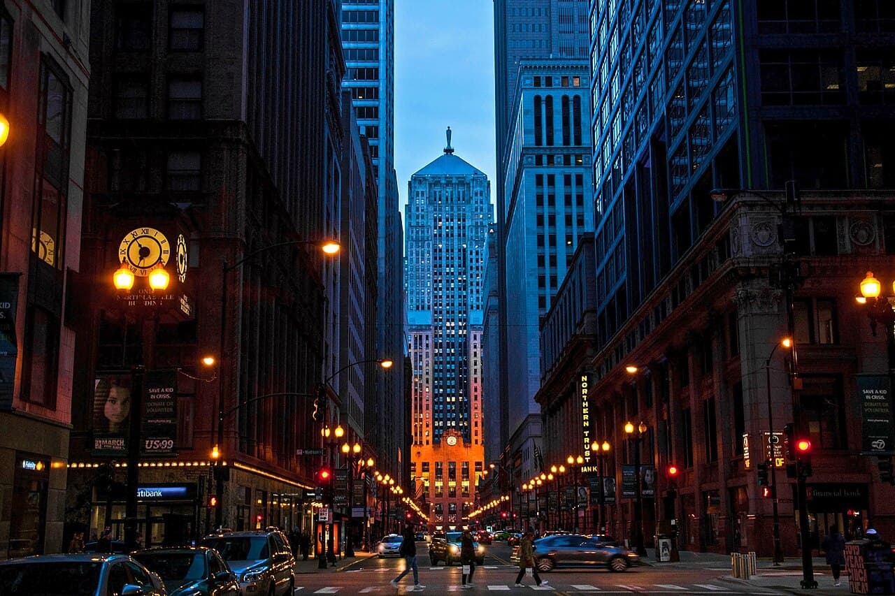 LaSalle Street in Chicago's financial district at dusk, looking toward the lit Chicago Board of Trade Building.