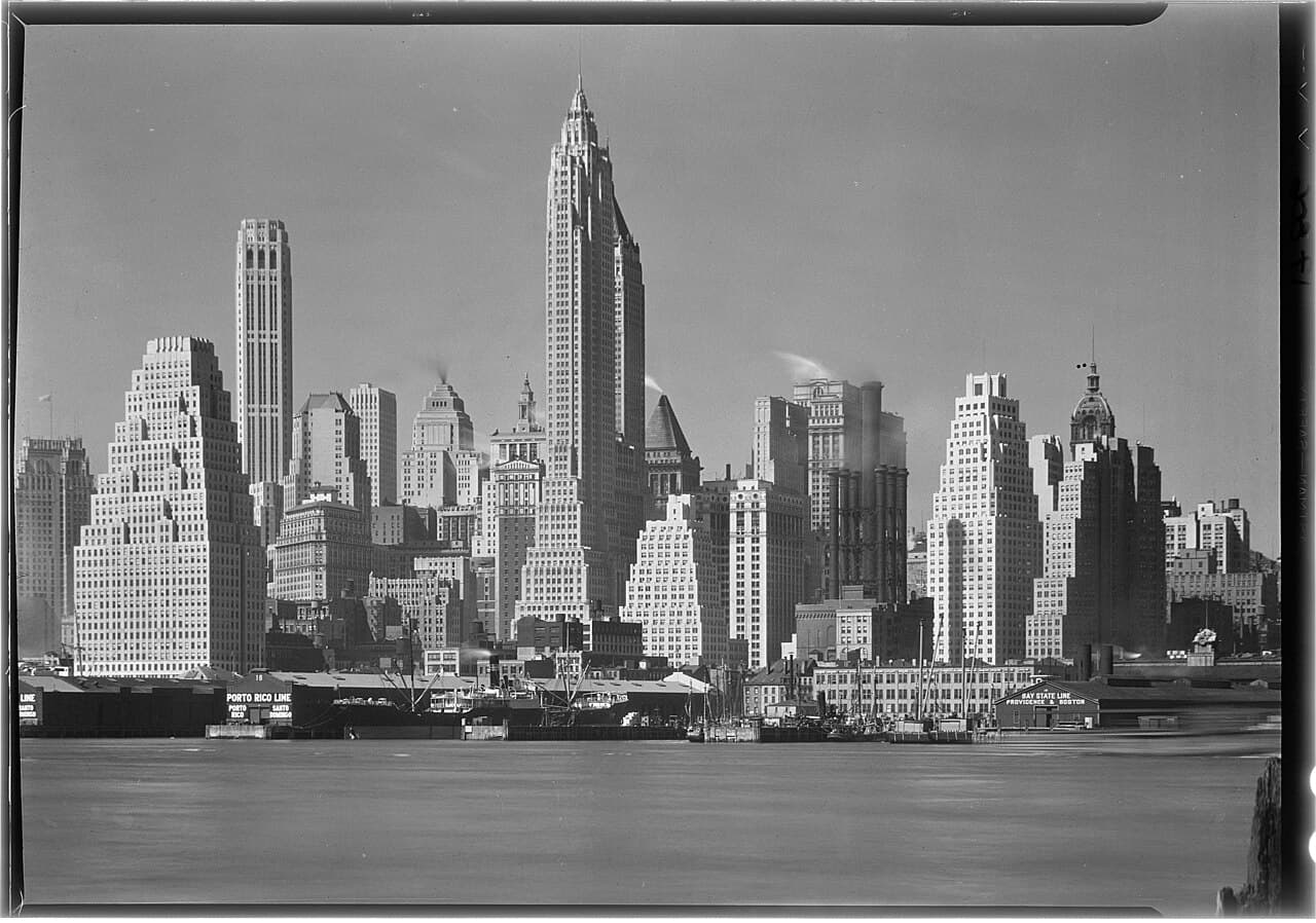 The Lower Manhattan skyline above the East River piers, photographed by Samuel H. Gottscho in 1932.