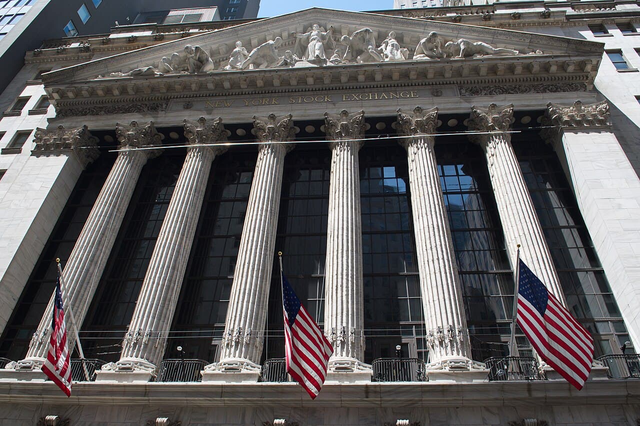 The columned Broad Street facade of the New York Stock Exchange building, hung with American flags.