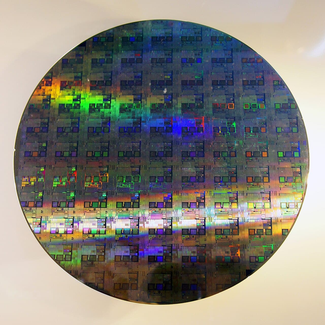 A 12-inch (300 mm) silicon wafer with iridescent patterned dies, before dicing.