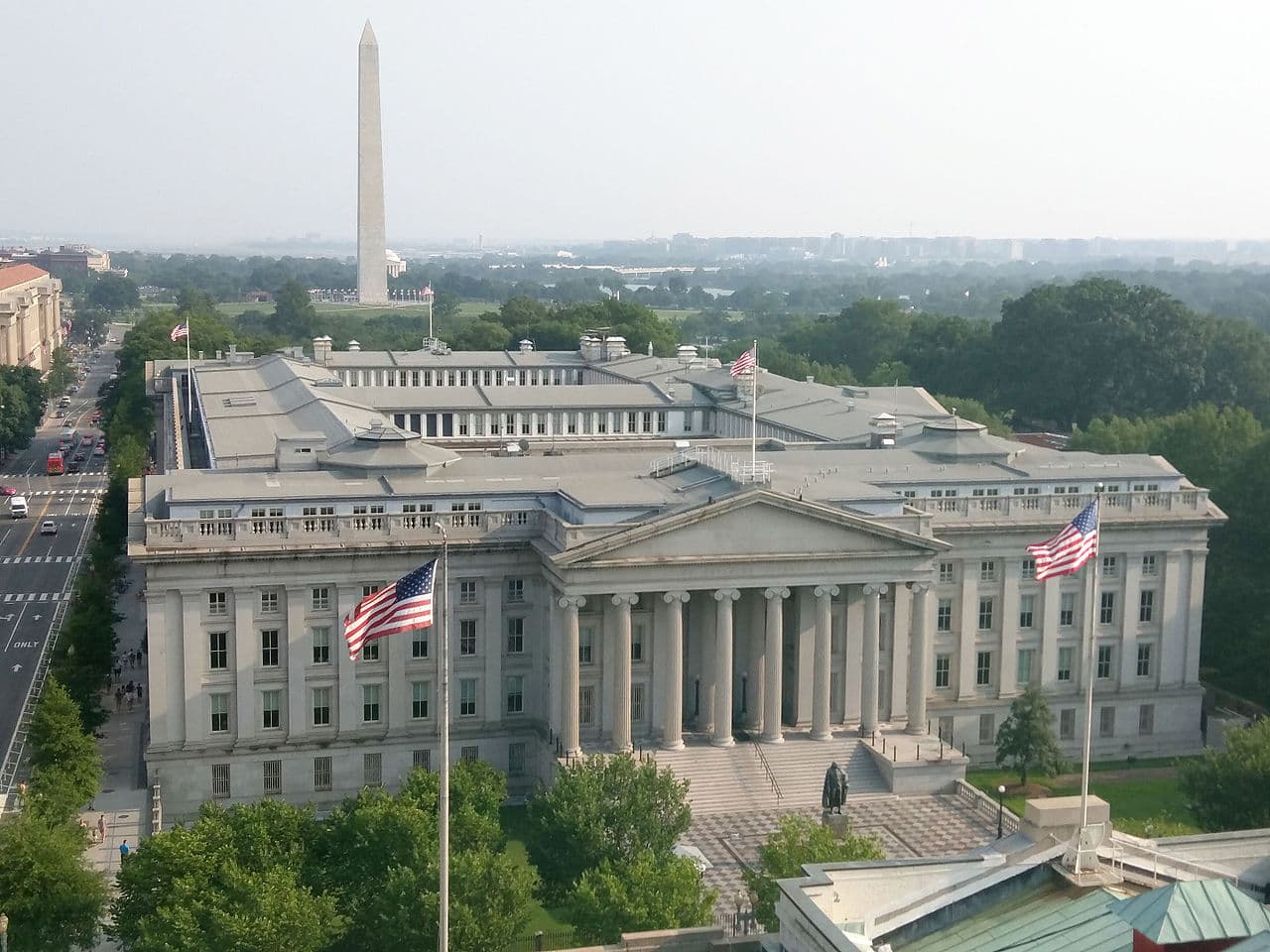 The U.S. Treasury Building in Washington, D.C., seen from above with the Washington Monument beyond.