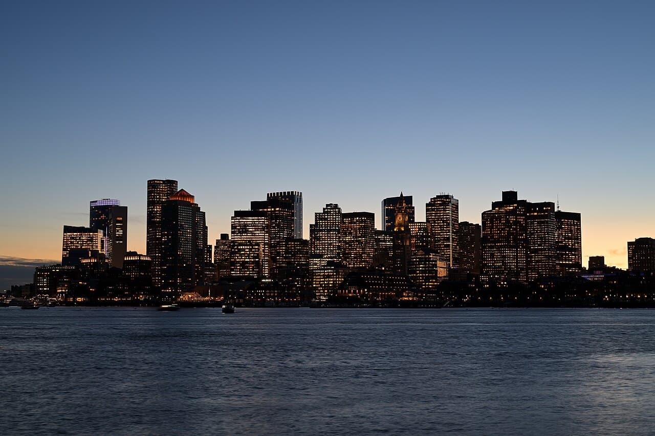 The Boston Financial District skyline at dusk, seen across the harbor from East Boston, November 2025.