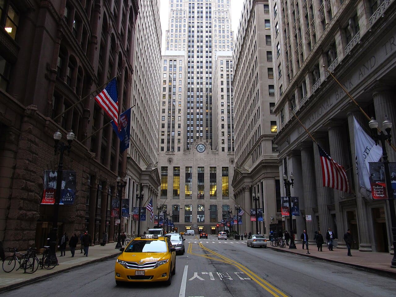 LaSalle Street in Chicago's Loop by day, flags flying, with the Chicago Board of Trade Building at the end of the street.